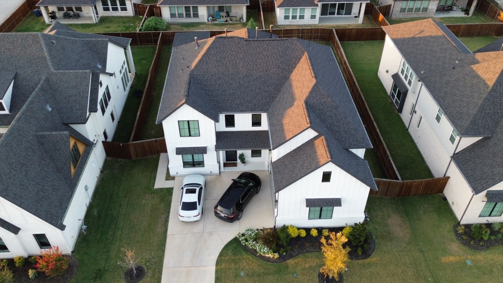 Aerial view of a completed roof on a modern white North Texas home